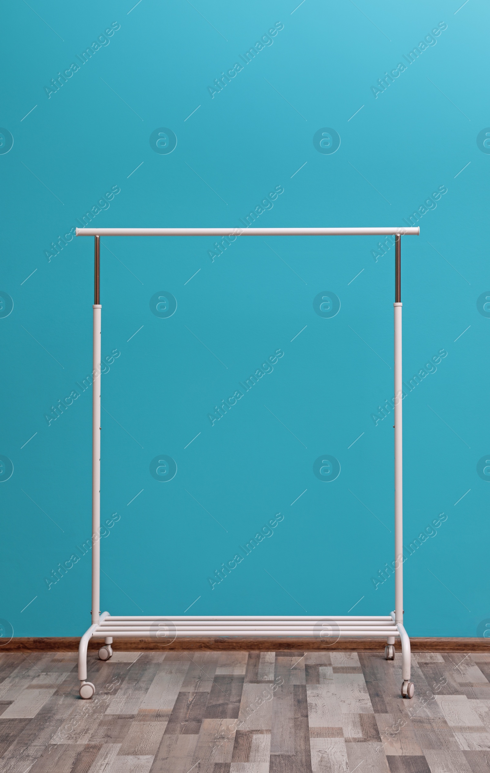 Photo of Empty wardrobe rack for clothing and shoes near color wall