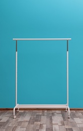 Photo of Empty wardrobe rack for clothing and shoes near color wall