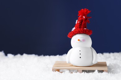 Photo of Cute decorative snowman on artificial snow against blue background. Space for text