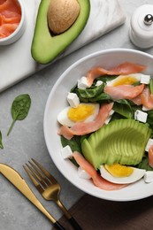 Photo of Delicious salad with boiled egg, salmon and avocado served on light grey marble table, flat lay