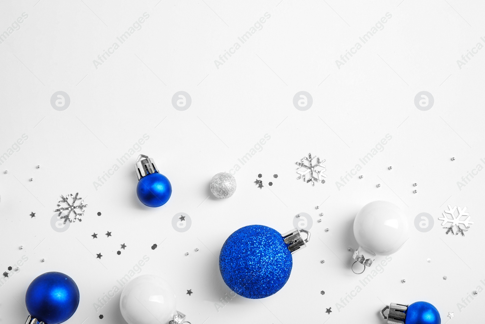 Photo of Colorful Christmas balls and sparkles on white background, top view