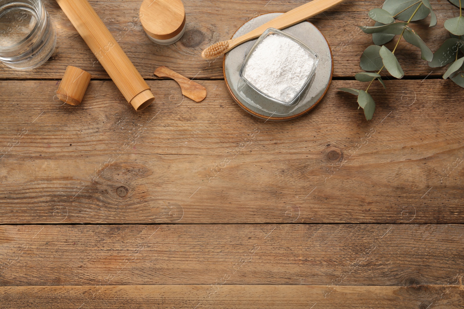 Photo of Flat lay composition with tooth powder and eucalyptus on wooden table, space for text