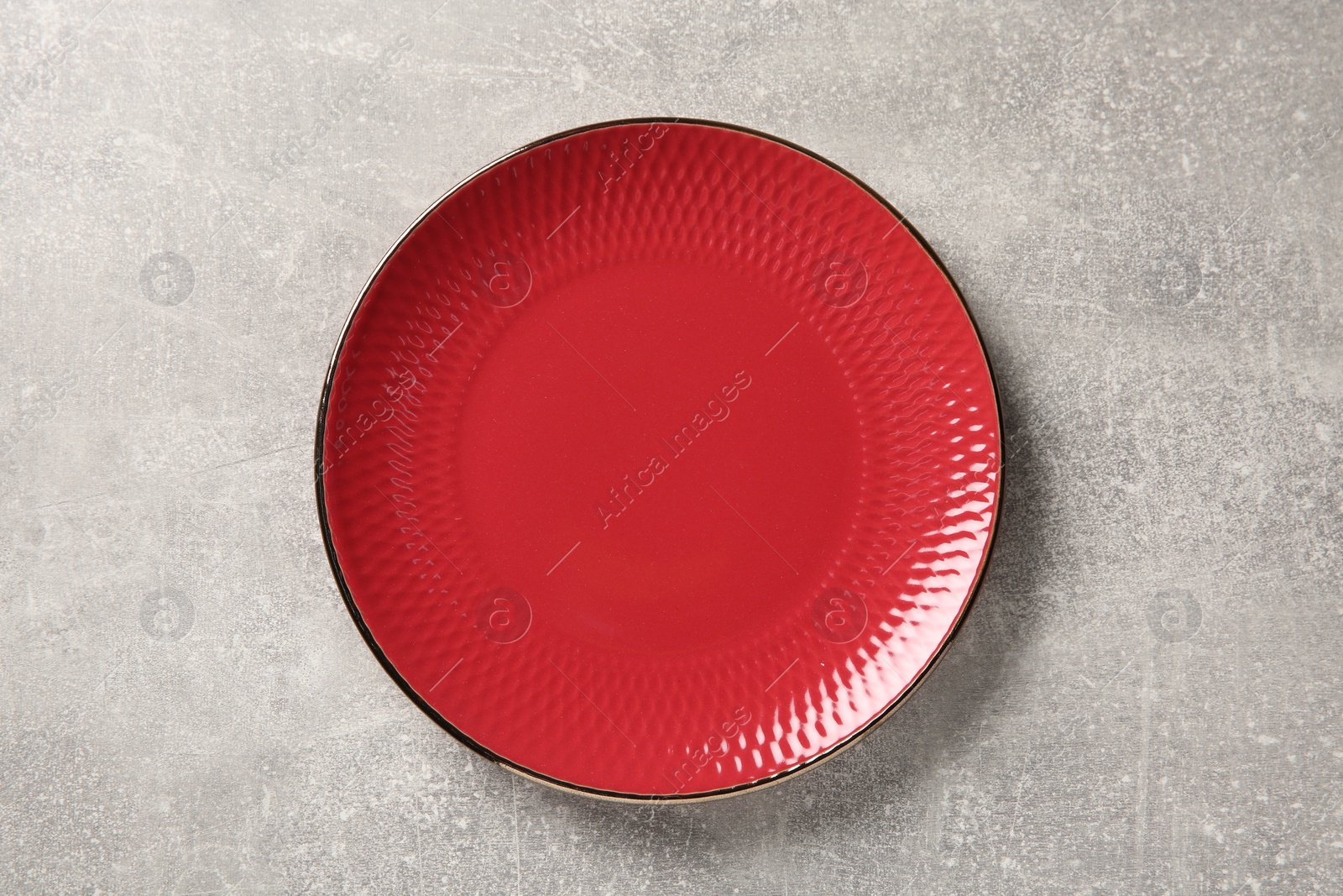 Photo of One red ceramic plate on light grey table, top view