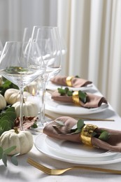 Beautiful autumn table setting. Plates, cutlery, glasses and floral decor indoors