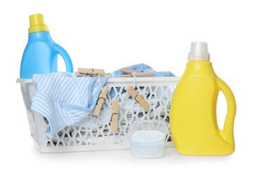 Basket with fresh baby laundry, washing powder and bottles of detergent on white background