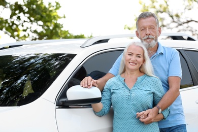 Photo of Happy senior couple posing near car outdoors