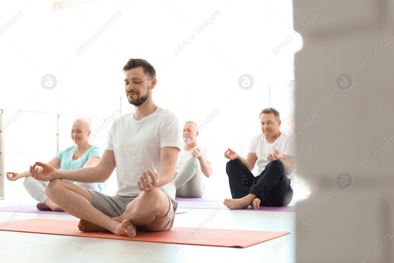 Photo of Group of people in sportswear practicing yoga indoors