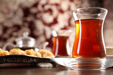 Traditional Turkish tea in glass on wooden table, closeup. Space for text