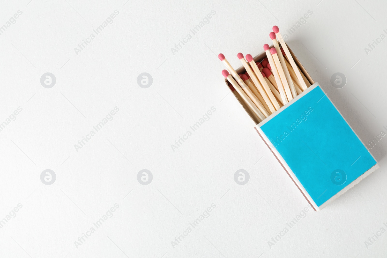 Photo of Cardboard box with matches on light background, top view. Space for design