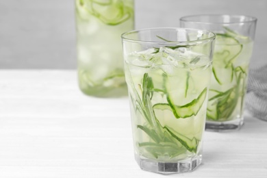 Photo of Glasses of refreshing cucumber lemonade on white table, space for text. Summer drink