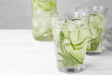 Glasses of refreshing cucumber lemonade on white table, space for text. Summer drink