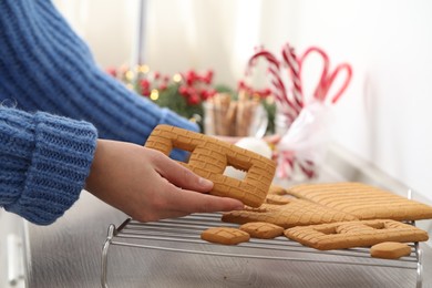 Woman making gingerbread house at wooden table, closeup