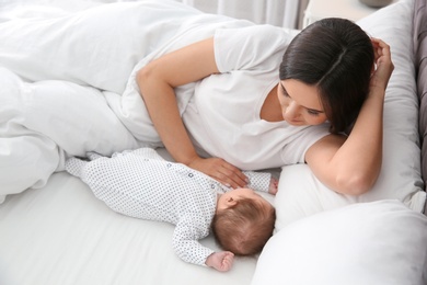 Photo of Happy woman with her sleeping baby on bed