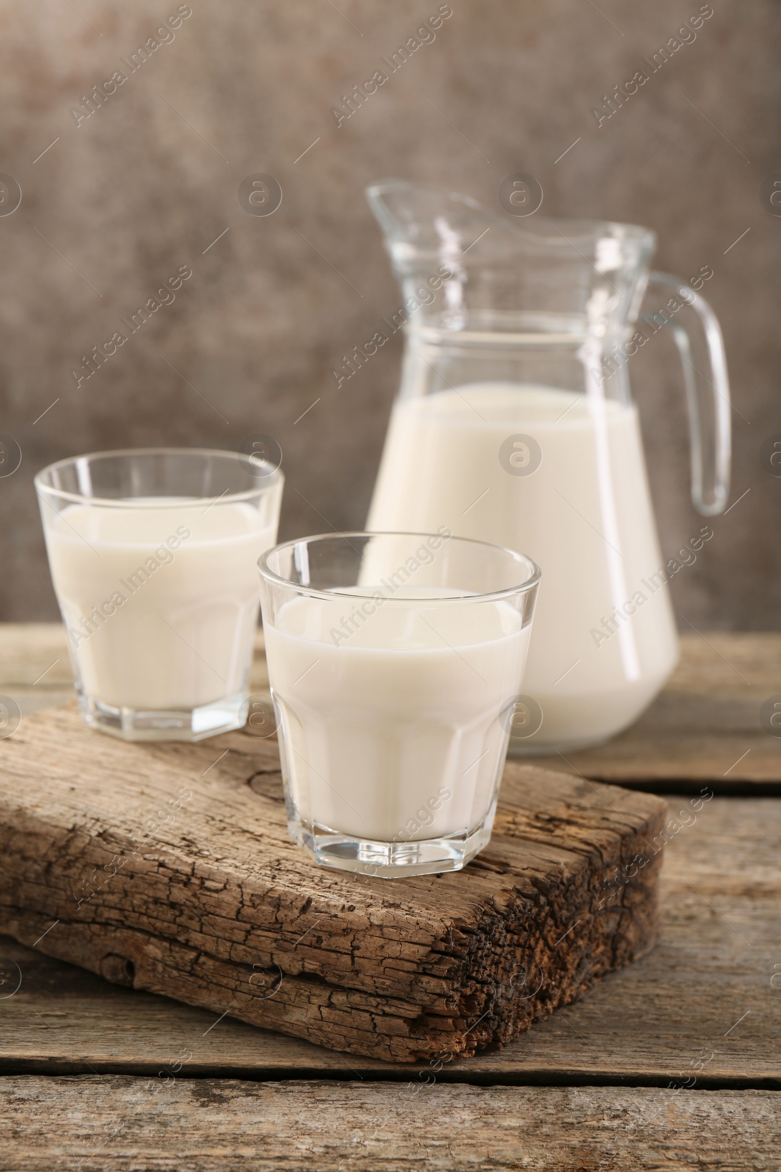 Photo of Jug and glasses of fresh milk on wooden table