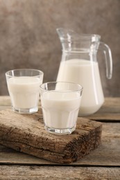 Jug and glasses of fresh milk on wooden table