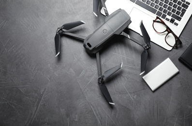 Photo of Modern drone with video camera and laptop on grey stone table, flat lay. Space for text