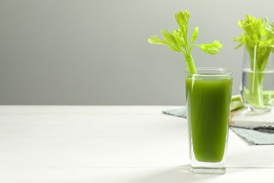 Glass of fresh celery juice on white table, space for text