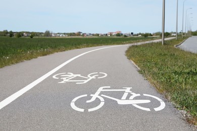 Bicycle lane with white sign painted on asphalt near sidewalk