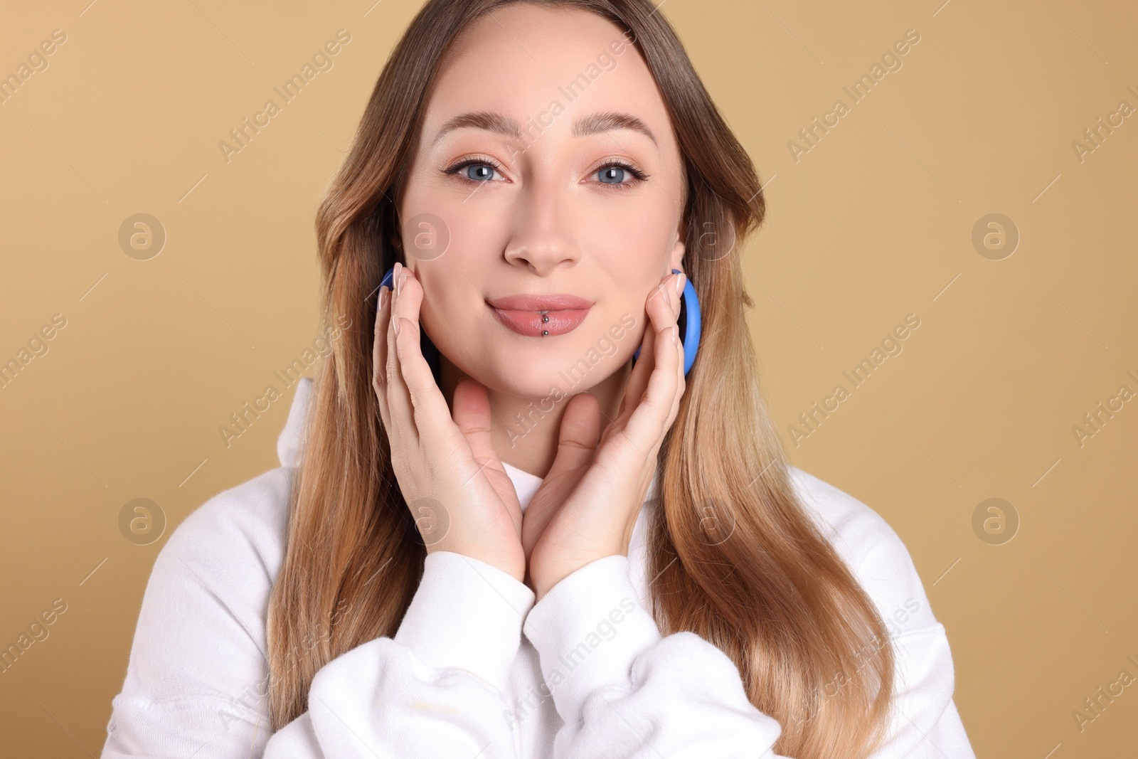 Photo of Young woman with lip piercing on beige background