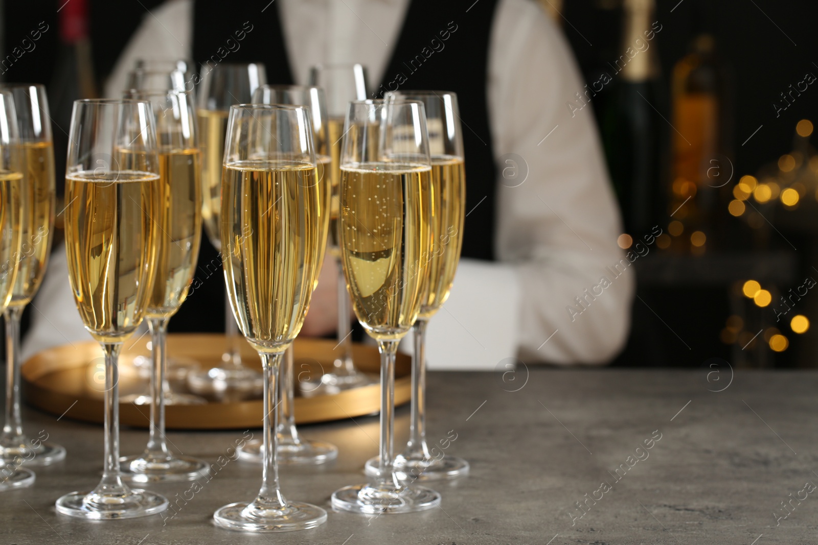 Photo of Glasses of champagne and waiter in restaurant. Space for text