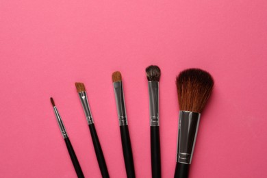 Photo of Set of makeup brushes on pink background, flat lay. Space for text