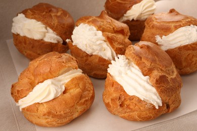 Photo of Delicious profiteroles with cream filling on table, closeup