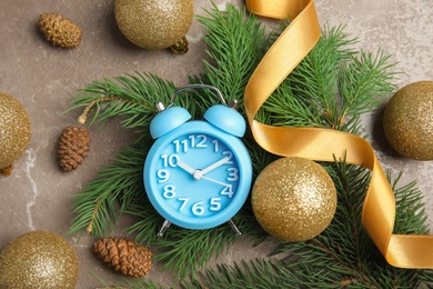 Photo of Flat lay composition with alarm clock, fir branches and decorations on grey background. Christmas countdown