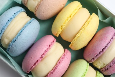 Photo of Many delicious colorful macarons in box on white background, top view