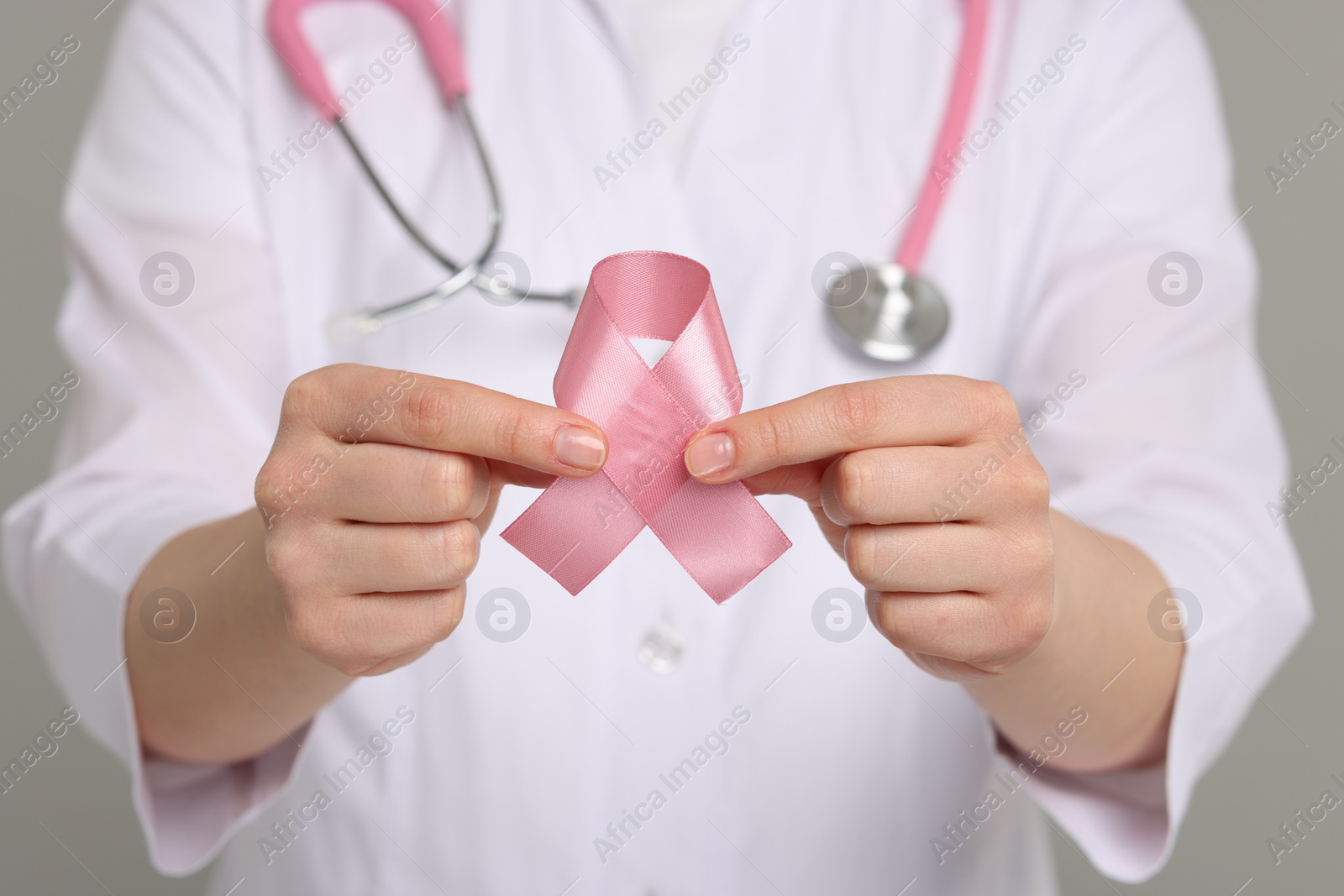 Photo of Mammologist with pink ribbon on gray background, closeup. Breast cancer awareness