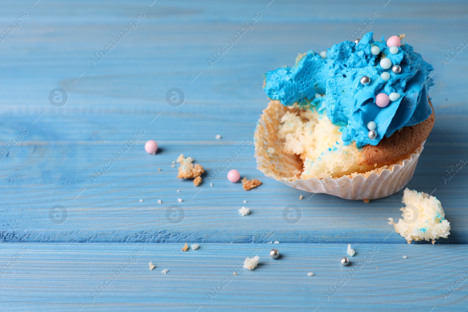 Photo of Failed cupcake on blue wooden table, closeup. Troubles happen