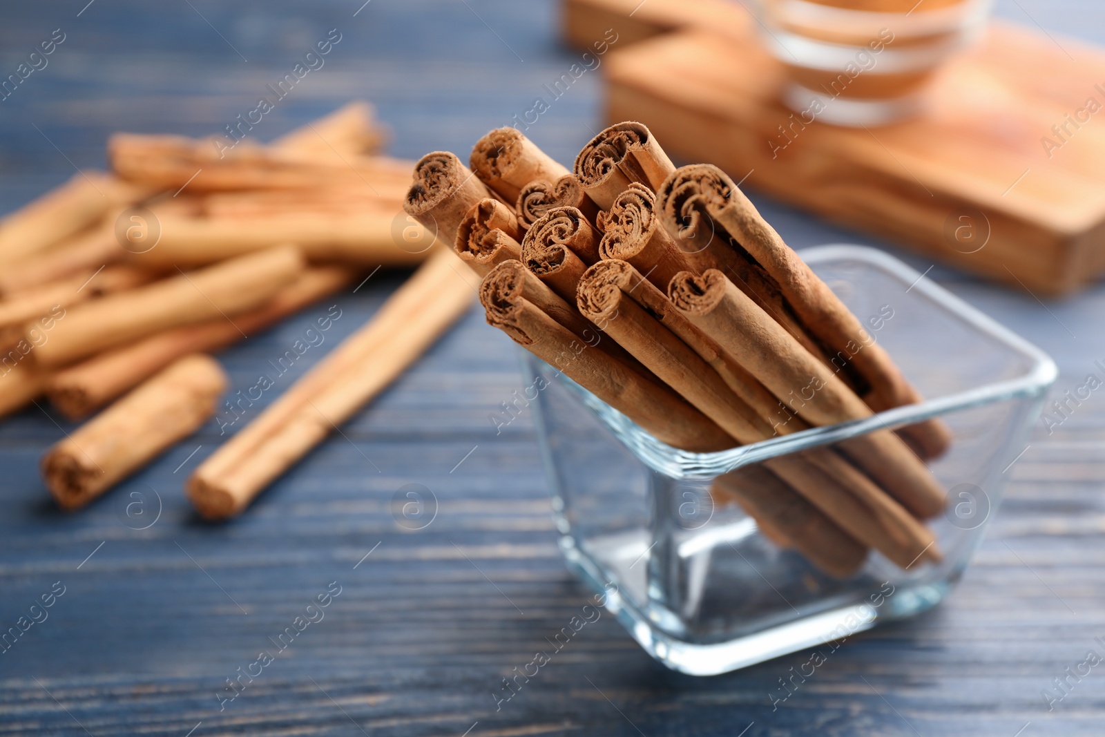 Photo of Aromatic cinnamon sticks on blue wooden table, closeup. Space for text