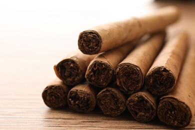 Photo of Many cigars on wooden table, closeup view