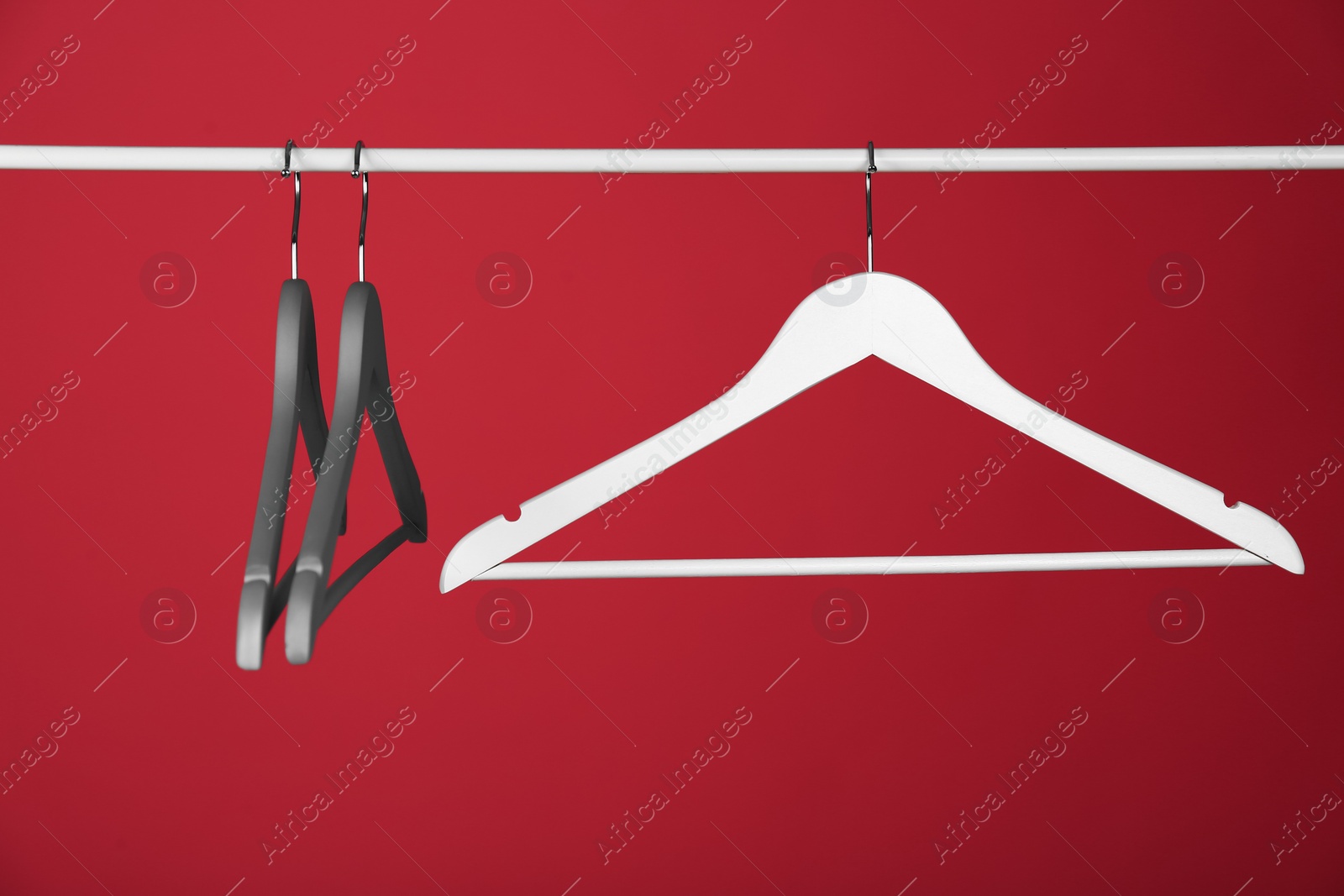 Photo of Empty clothes hangers on metal rail against color background. Space for text