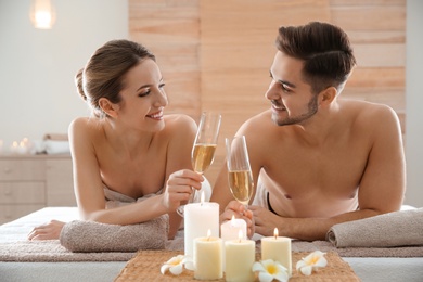 Photo of Romantic young couple with champagne in spa salon