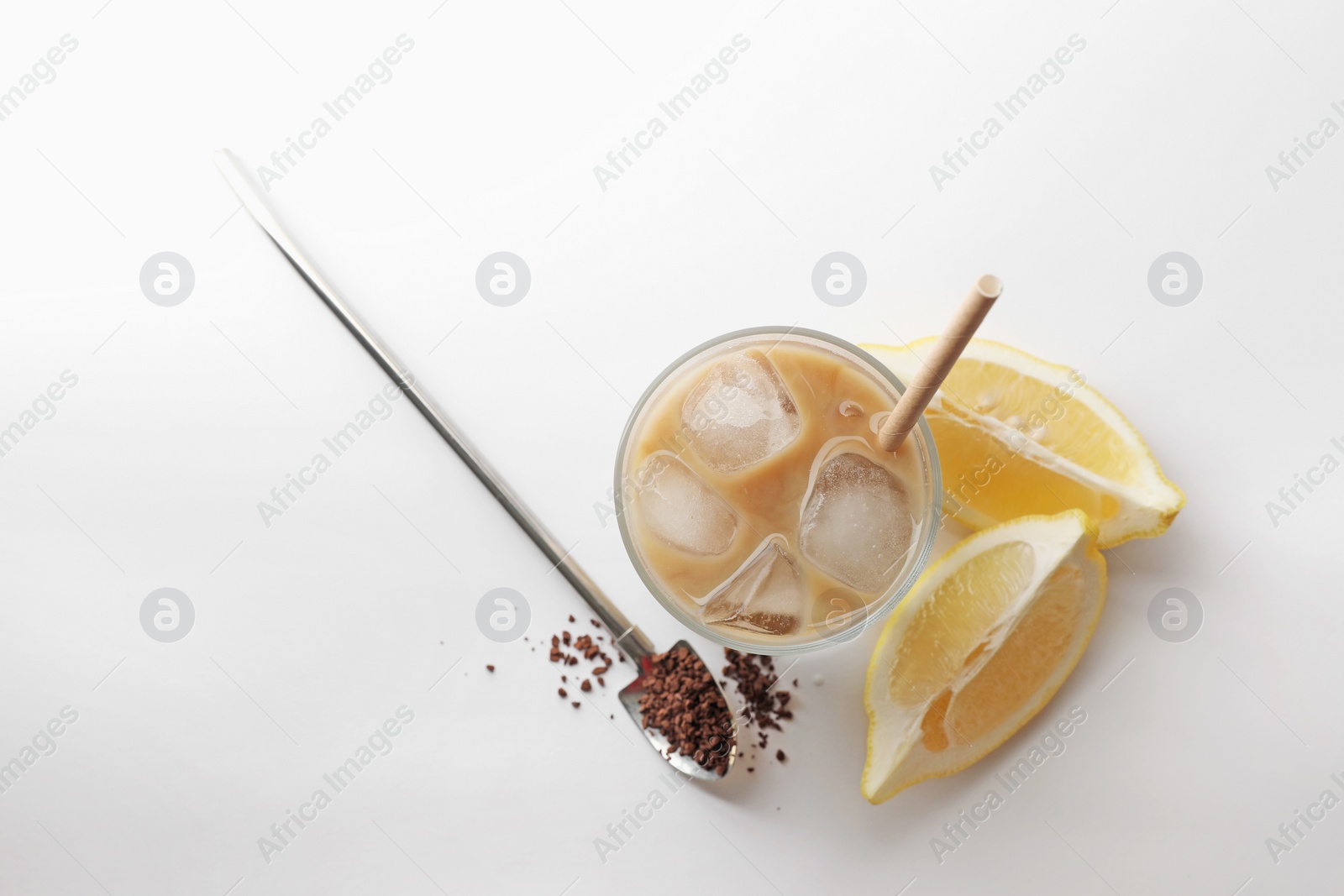 Photo of Iced coffee with milk in glass, cut lemon and instant coffee on white background