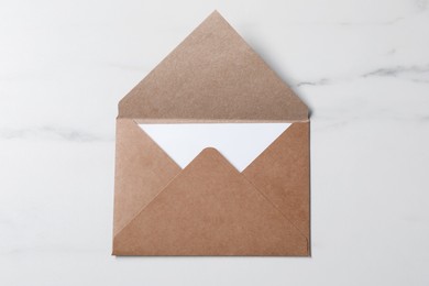 Photo of Letter envelope with card on white marble table, top view