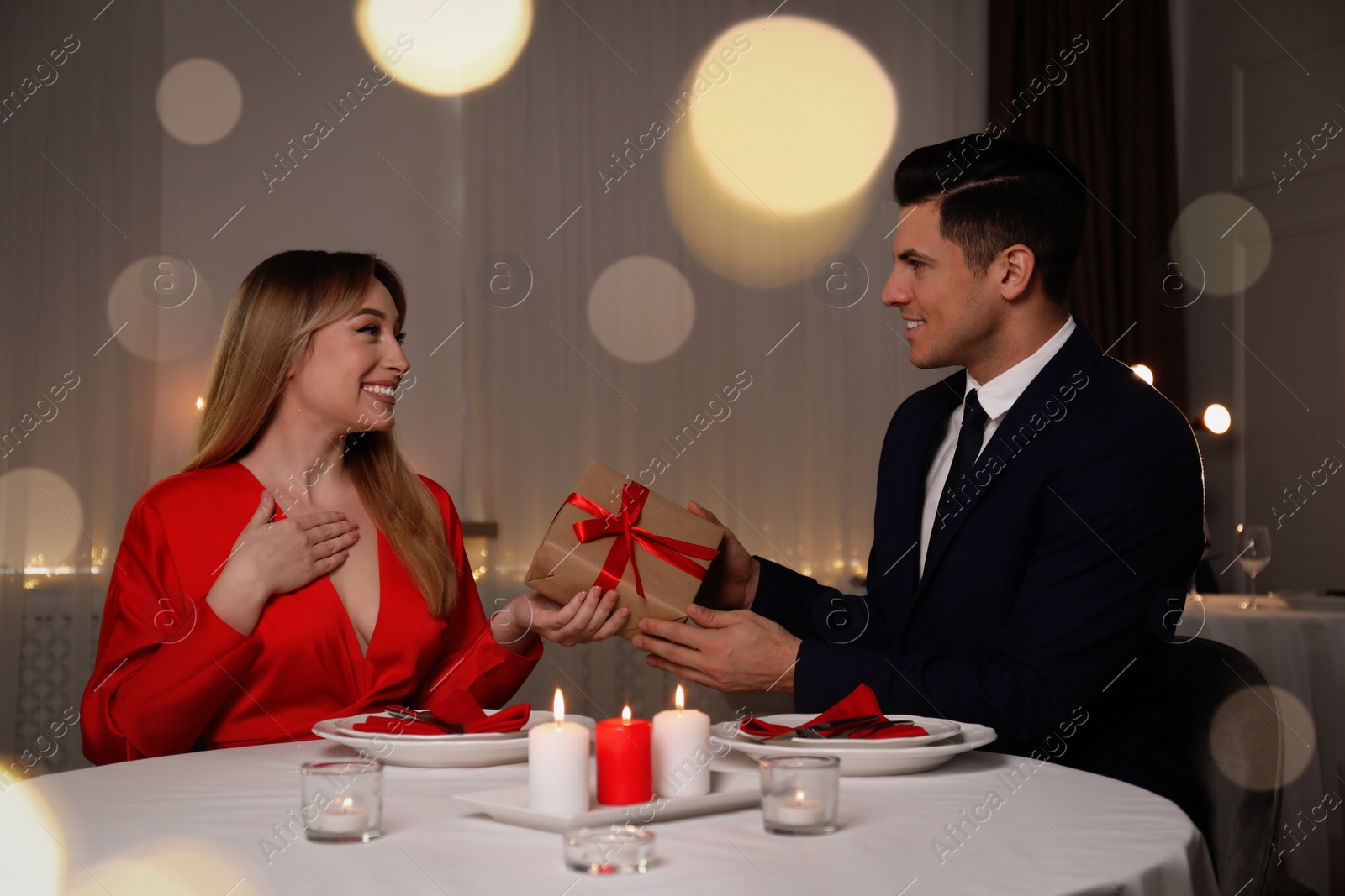 Photo of Man presenting gift to his beloved woman in restaurant at romantic dinner