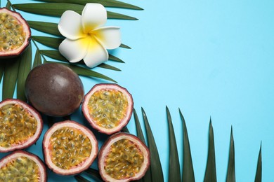 Photo of Passion fruits (maracuyas), flower and palm leaves on light blue background, flat lay. Space for text