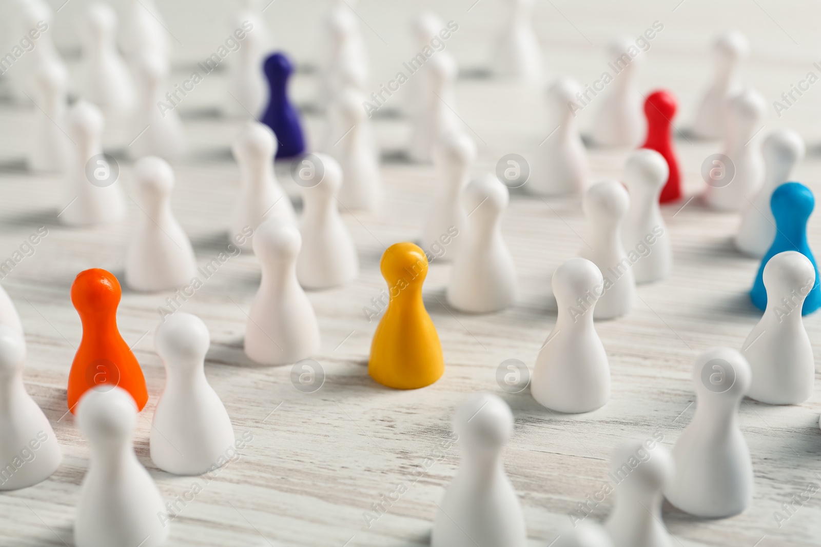 Photo of Colorful pawns on white wooden table, closeup. Social inclusion concept