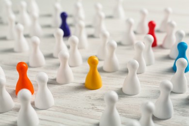 Colorful pawns on white wooden table, closeup. Social inclusion concept