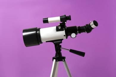 Photo of Tripod with modern telescope on purple background, closeup