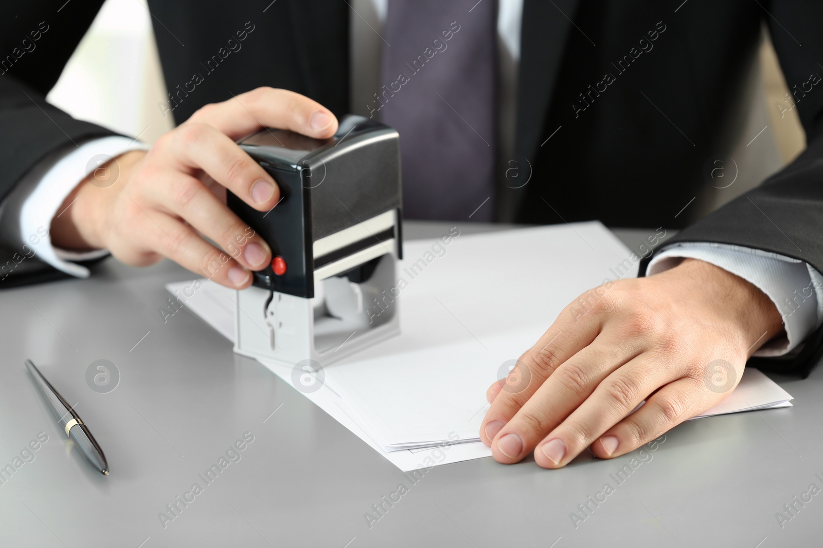 Photo of Male notary stamping document at table, closeup