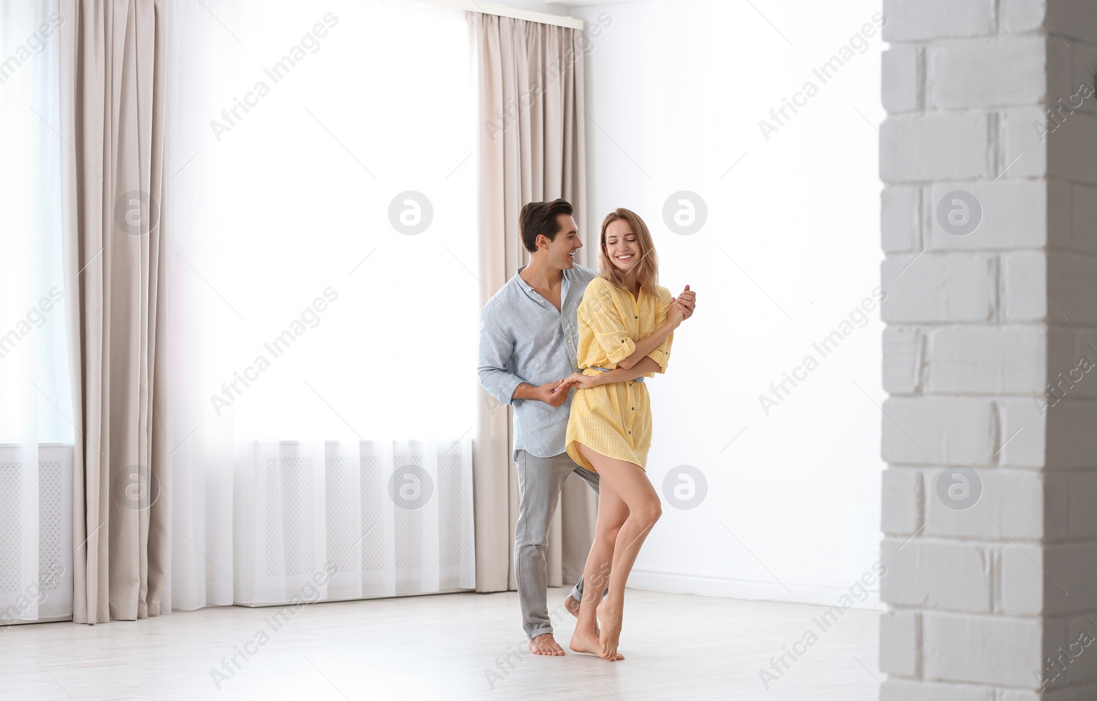 Photo of Beautiful young couple dancing in room at home