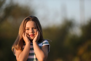 Portrait of cute little girl outdoors, space for text. Child spending time in nature