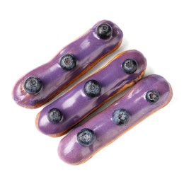 Delicious eclairs decorated with blueberries isolated on white, top view