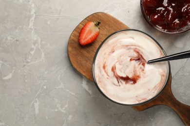 Photo of Tasty yoghurt with jam and strawberry on grey table, flat lay. Space for text