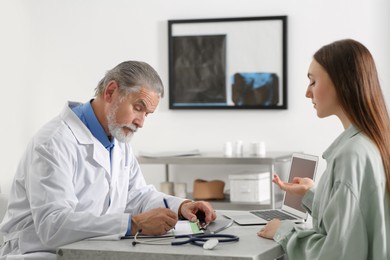 Photo of Professional orthopedist consulting patient at table in clinic