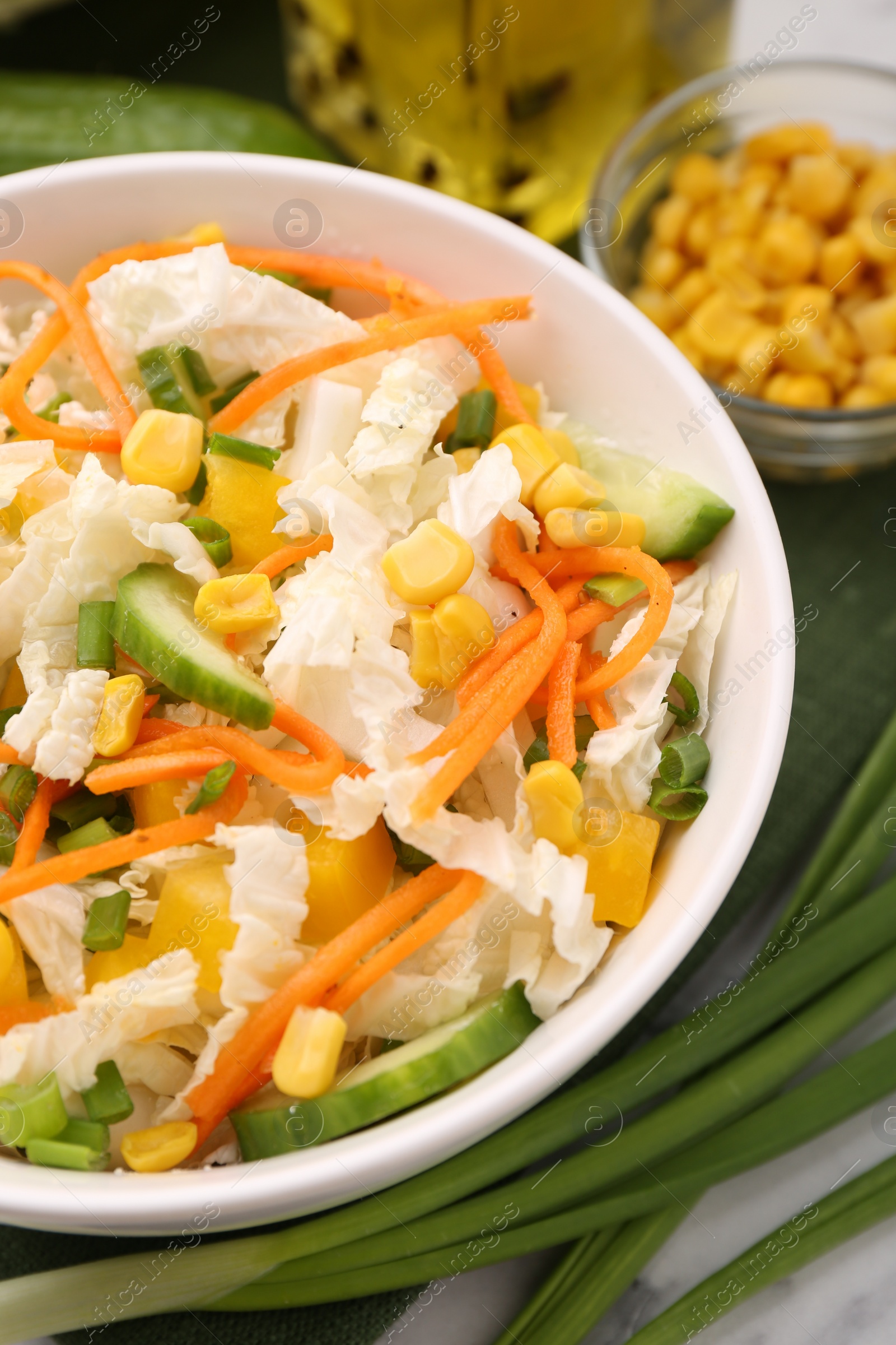 Photo of Tasty salad with Chinese cabbage, carrot, corn, cucumber and green onion on table, closeup