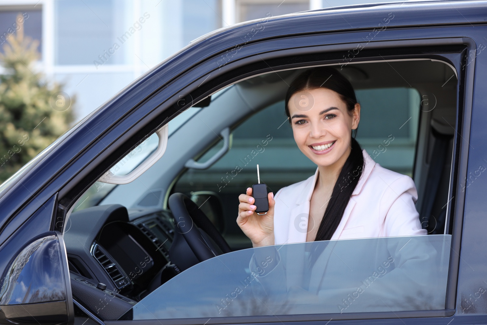 Photo of Young woman with key sitting in car outdoors. Buying new auto