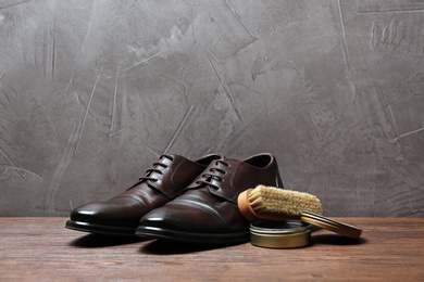 Photo of Leather footwear and shoe shine kit on wooden surface, space for text